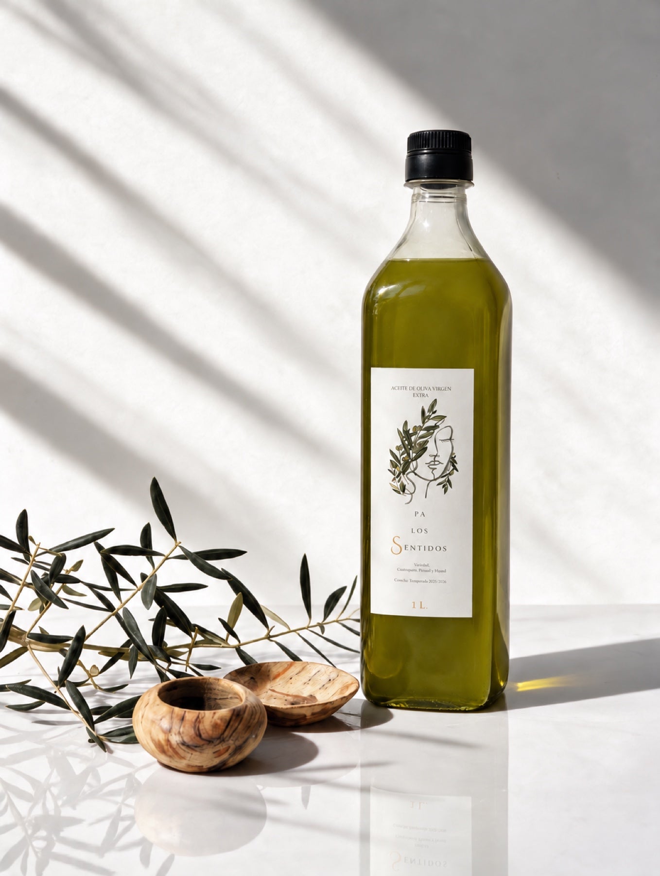 Botella de un litro de aceite Pa los Sentidos en una composición con ramas de olivo