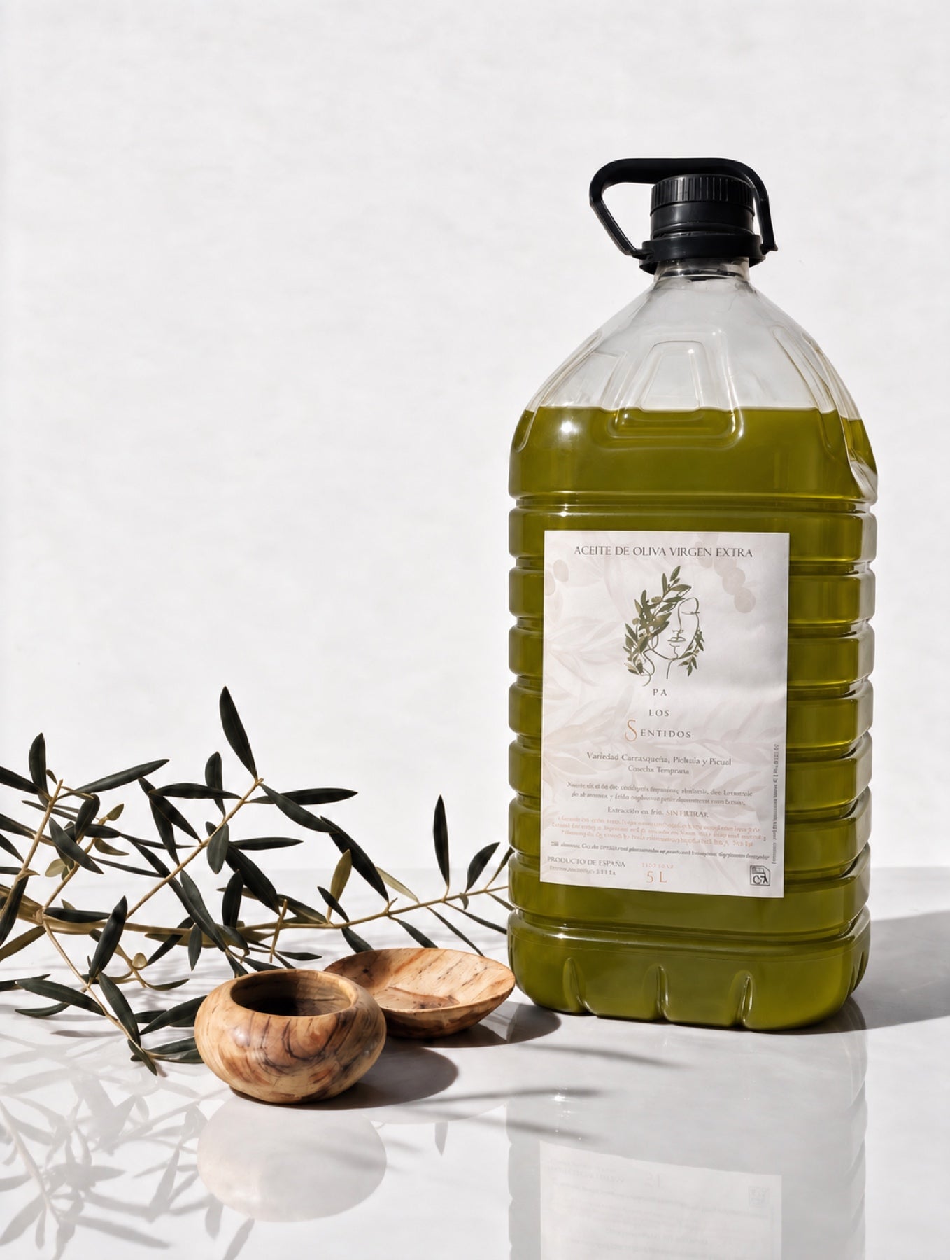 Garrafa de cinco litros de aceite Pa los Sentidos en una composición con ramas de olivo